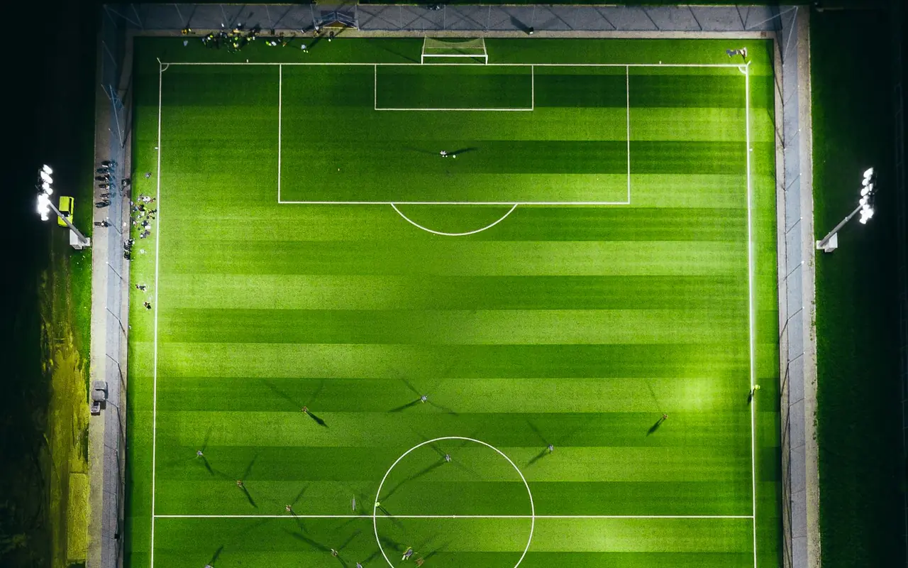 Sports field illuminated at night by pole-mounted field lighting