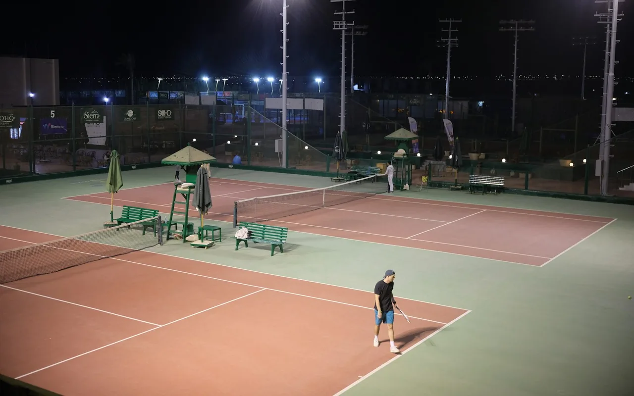 Tennis courts illuminated at night by court lighting