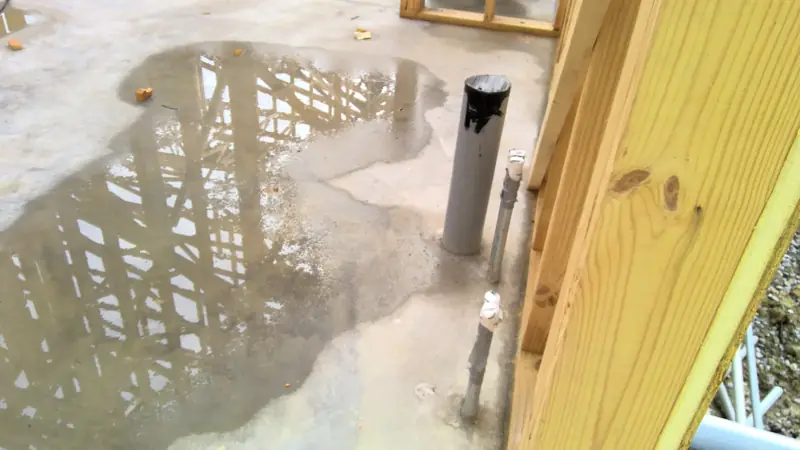 PVC conduit and electrical stubs coming through a concrete slab next to wood framing