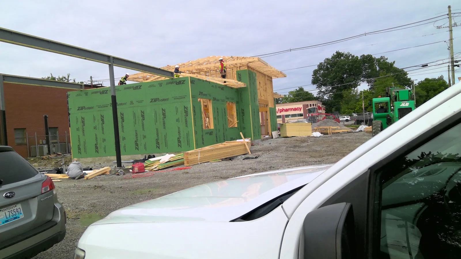 A bank branch under construction with green wall sheathing and wooden roof trusses being installed