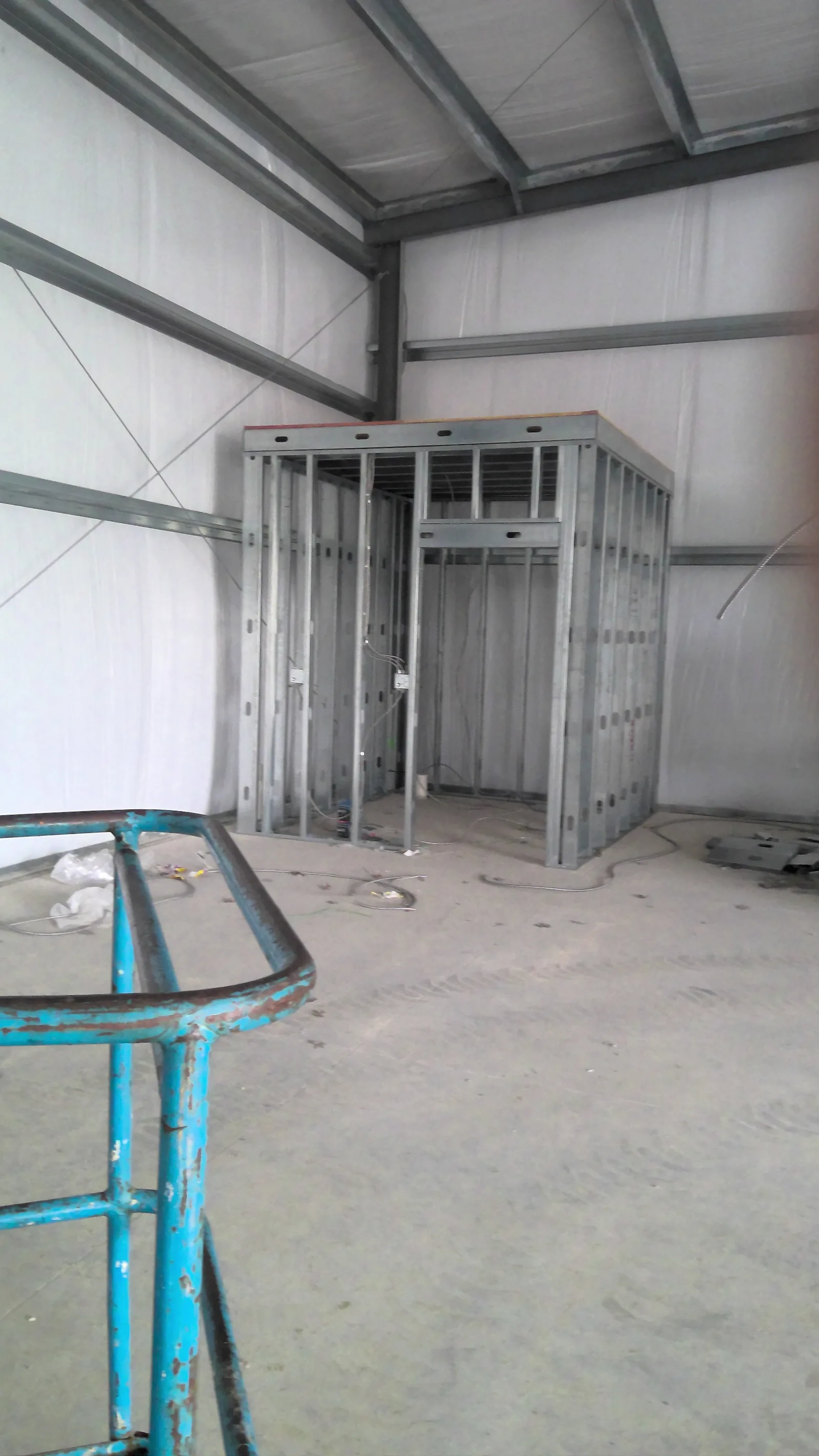 Interior warehouse view of metal wall studs and electrical wiring for a small office room