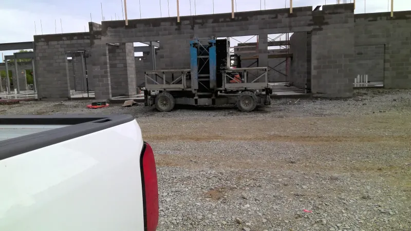 Construction site with a white truck tail light and heavy lifting equipment near concrete block walls