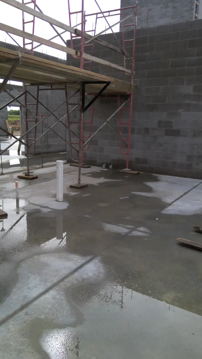 Interior concrete floor with red scaffolding and gray block walls at a new hotel construction site