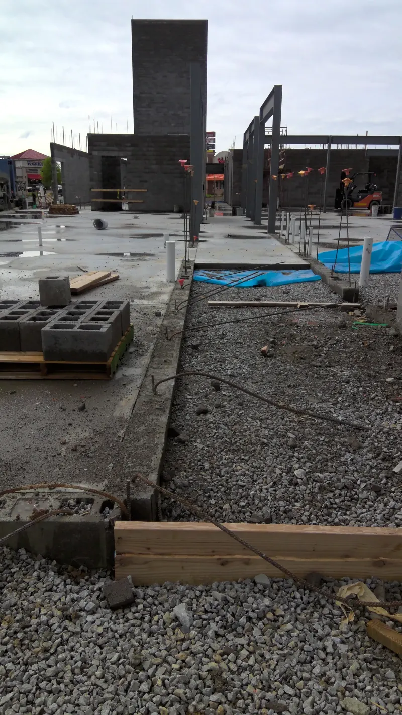 Concrete slab and gravel ground at a hotel construction site with cinder blocks and steel frames