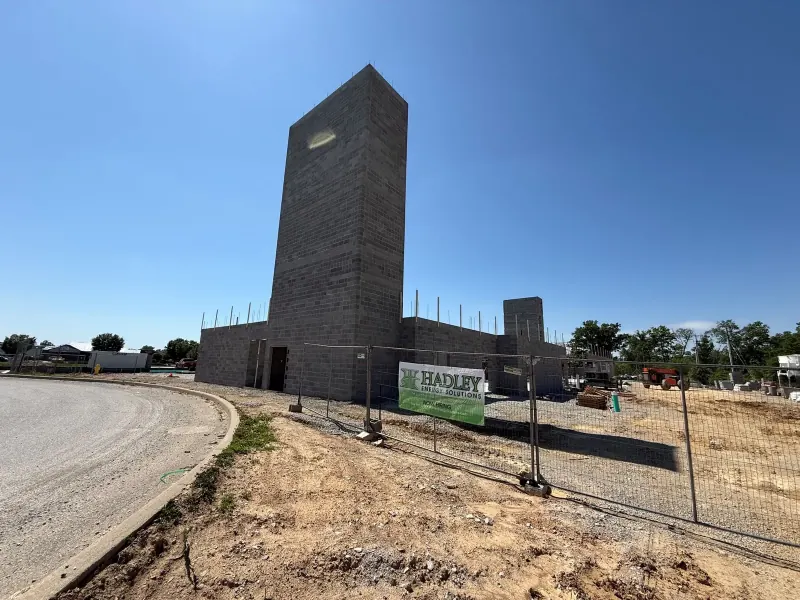 A masonry elevator shaft and concrete block walls at a hotel construction site with a company sign